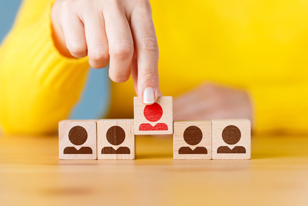 people icons on wooden blocks with one color red standing out