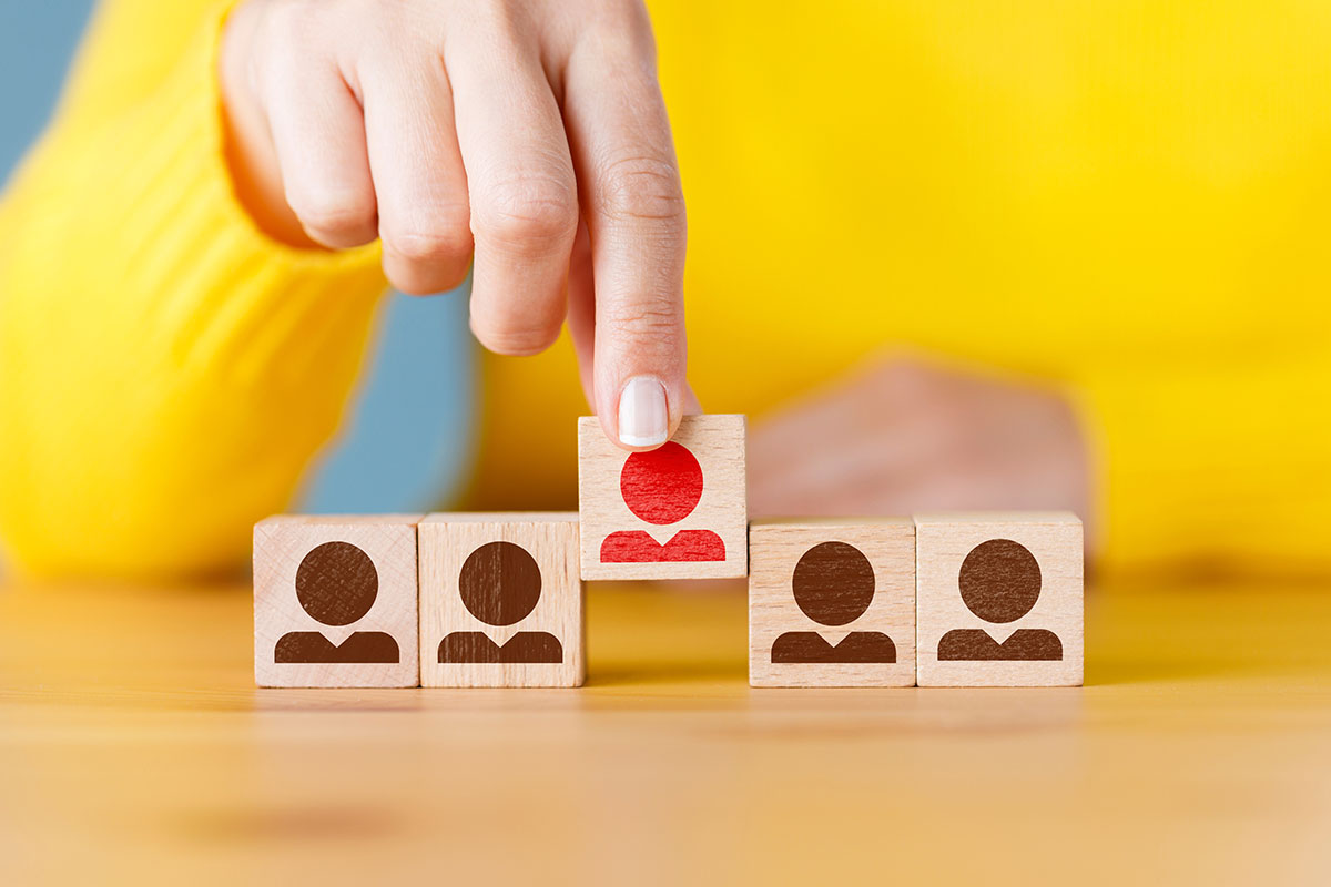 people icons on wooden blocks with one color red standing out